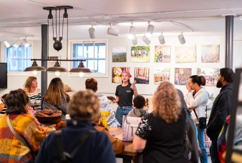 A group of people standing in a store listening to a girl give a lesson during a tour