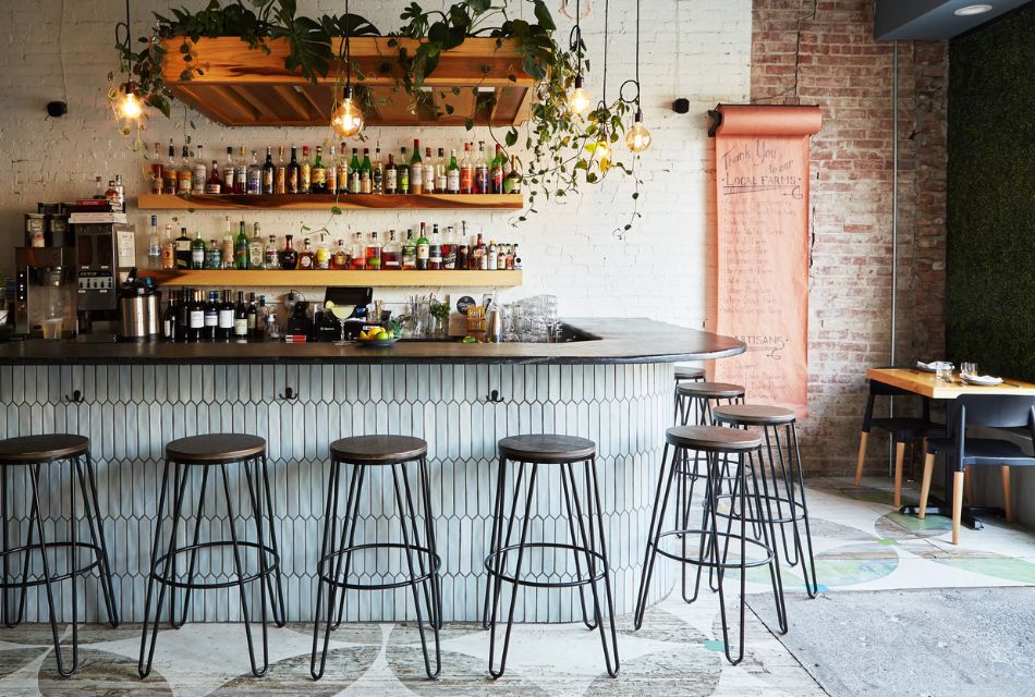 A curved bar in a restaurant with several bar stools and floating shelves full of bottles