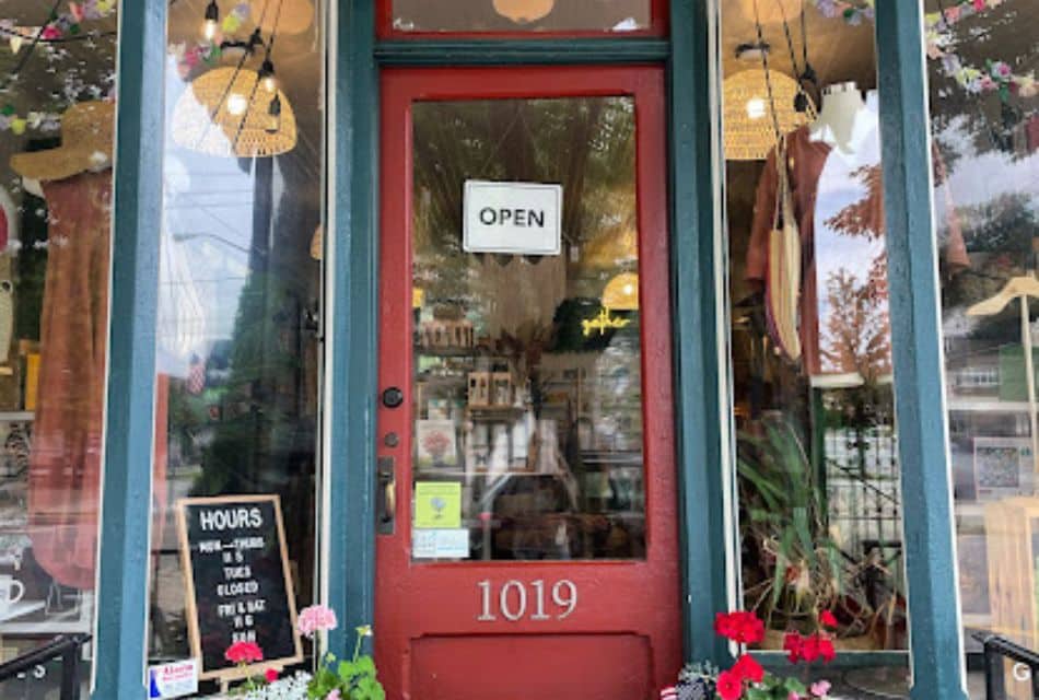 The front door and windows of a store with an open sign and mannequins in the windows