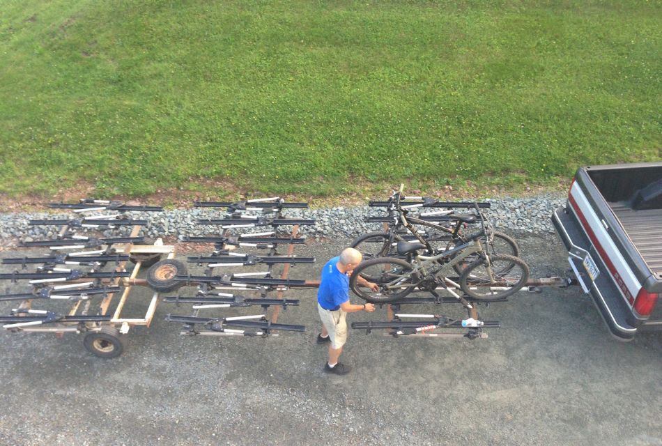 A man tending to some bikes on a large trailer for bicycles being pulled by a truck