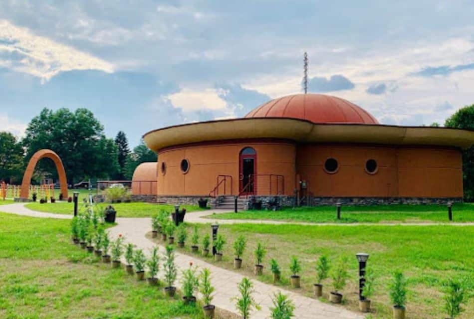 A very unique curved building with a domed roof and sidewalks lined with potted plants