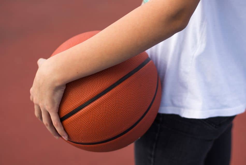 A person in black jeans and a white t-shirt holding a basketball