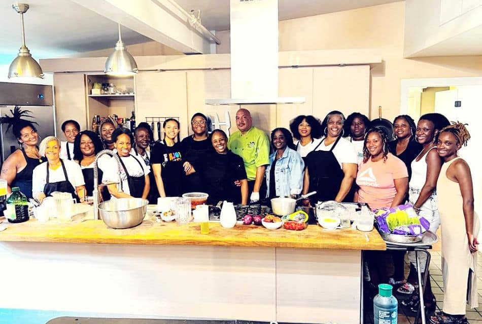 A large group of people standing in a kitchen counter together