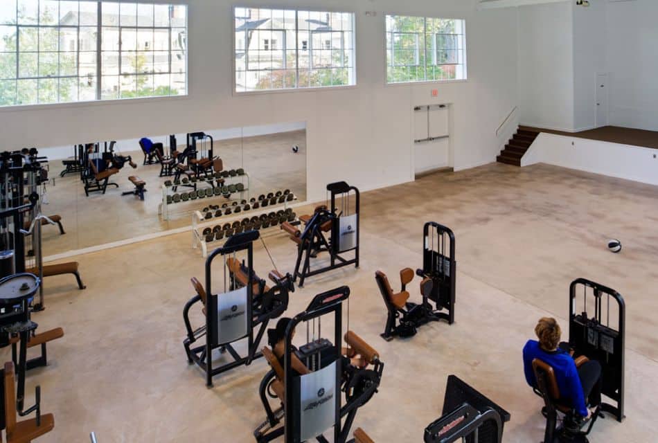 A large workout area with various machines, weight set and wall of mirrors