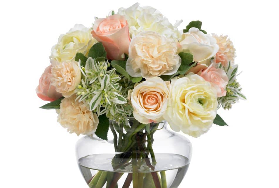 A clear vase with water holding a bouquet of white, cream, pink and peach colored flowers