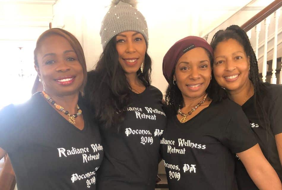 Four women in matching black and white t-shirts standing close together for a picture