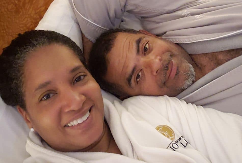 A man and woman in plush robes laying down together smiling