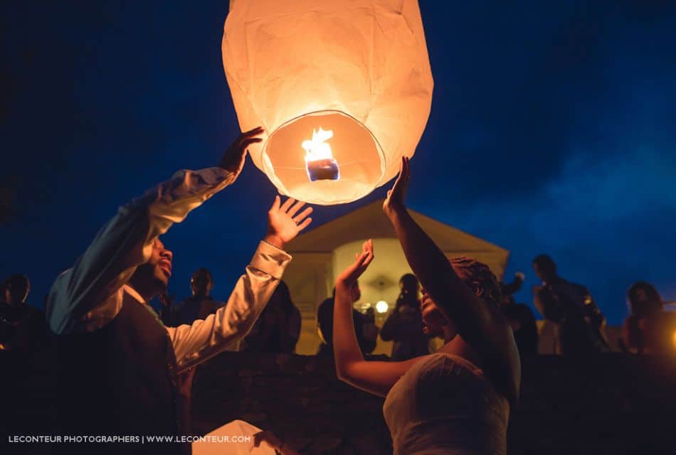 A bride and groom outside at night letting a floating lantern go up into the night sky