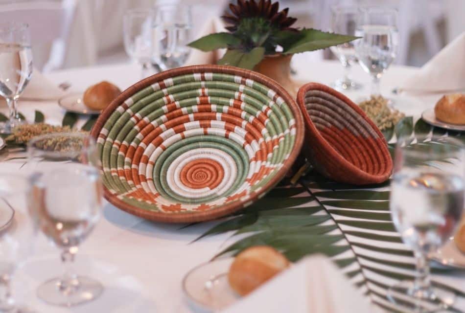 Two unique woven basket bowls serving as decoration on a white table with leafy branches